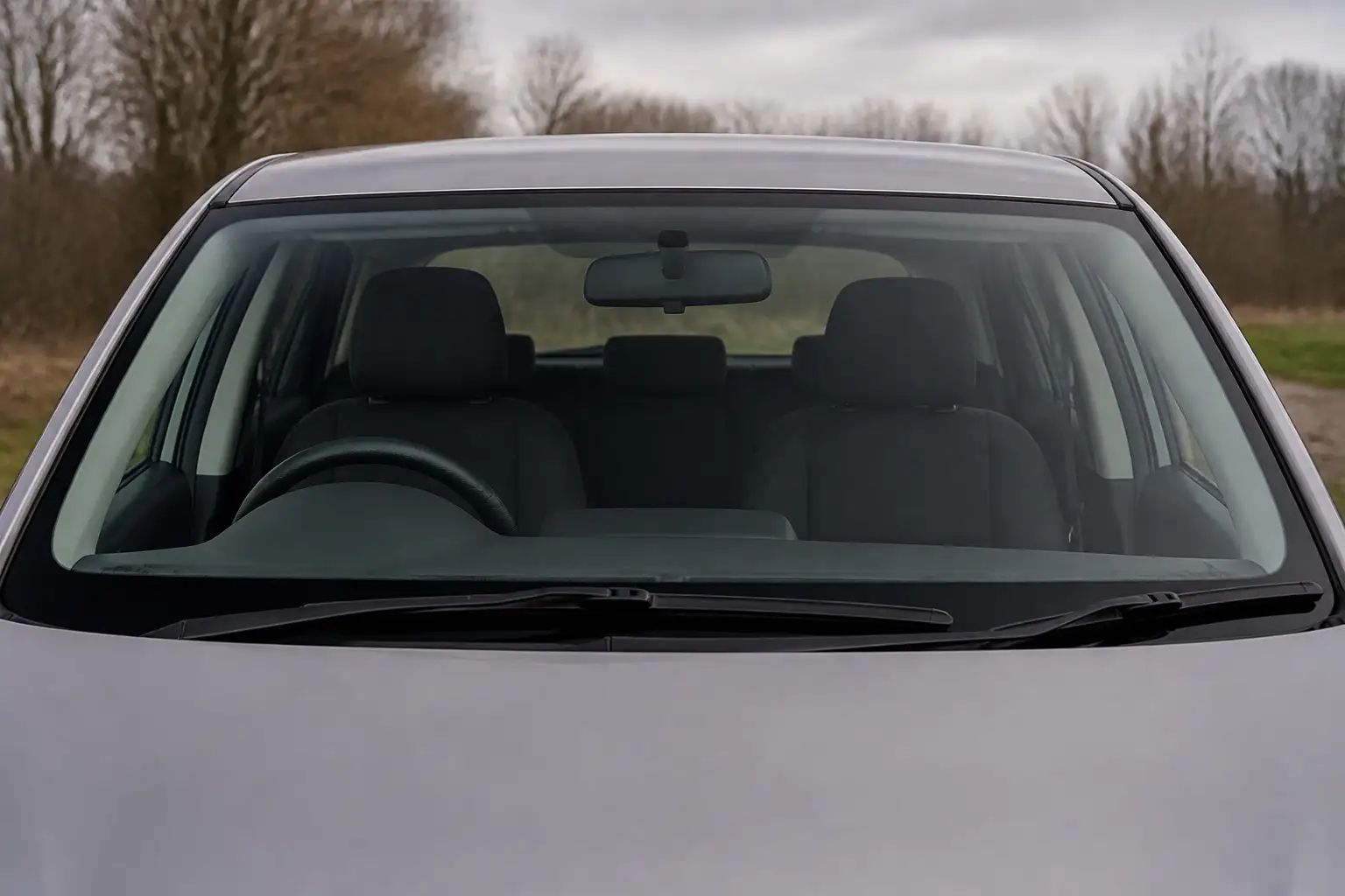 Frontansicht eines geparkten Autos mit klarer, unbeklebter Windschutzscheibe, durch die Lenkrad und leere Vordersitze zu sehen sind