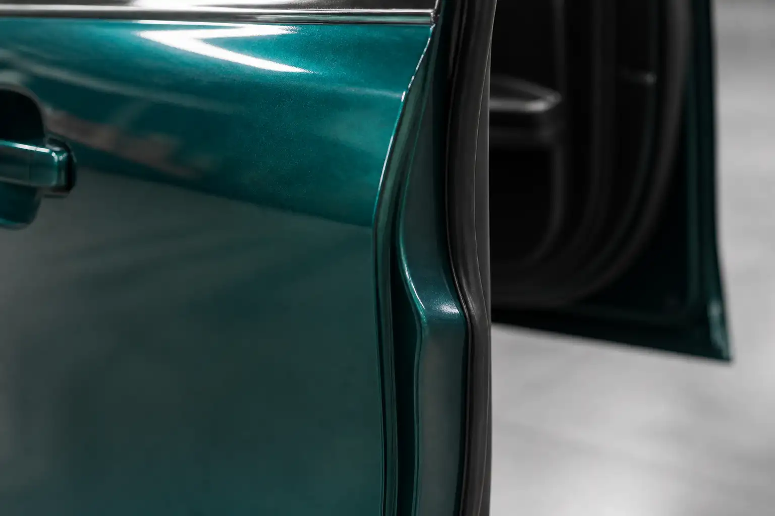 Nahaufnahme einer Autotür mit glänzender petrolgrüner Metallic-Folie, die sauber um die Türkante in den Spalt umgeschlagen ist