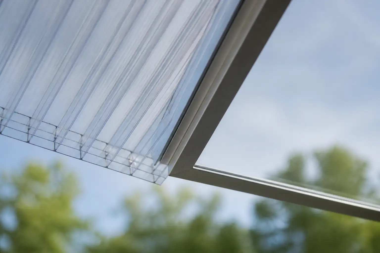 Transparente Doppelstegplatte aus Polycarbonat mit sichtbaren Hohlkammerstegen neben einer klaren Acrylglasplatte im Aluminiumrahmen