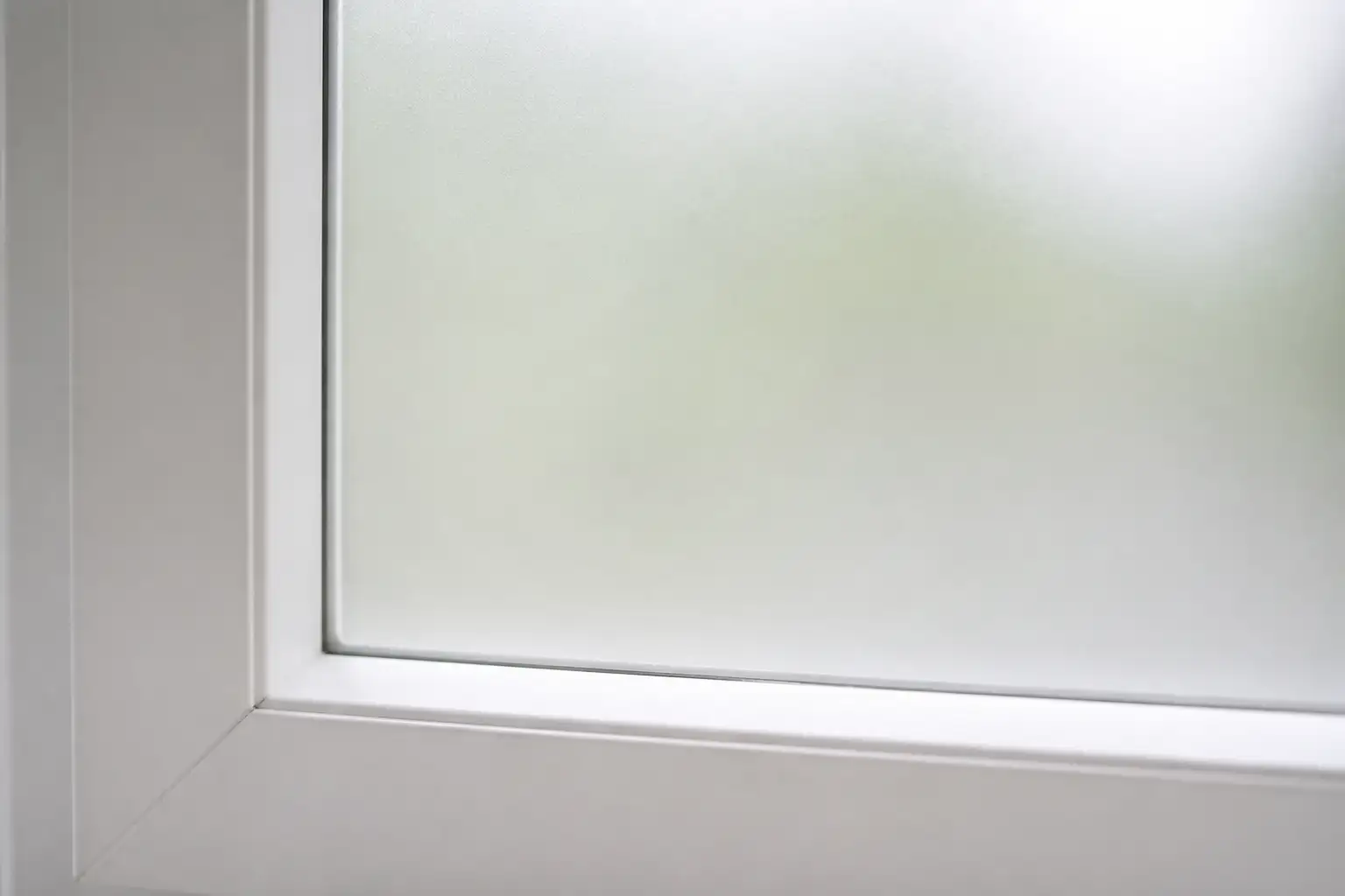 Fertig verklebte Milchglasfolie an einem weißen Fensterrahmen, die Folienkante läuft gleichmäßig parallel zum Rahmen
