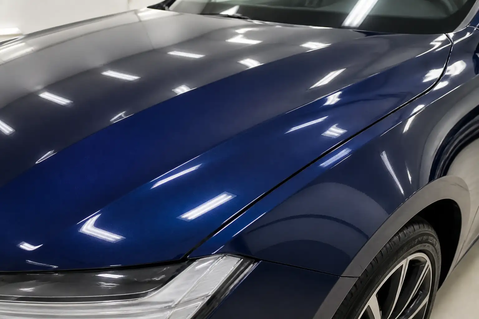 Motorhaube und Kotflügel eines dunkelblauen Autos mit glänzendem Originallack ohne Folie und ohne Klebereste