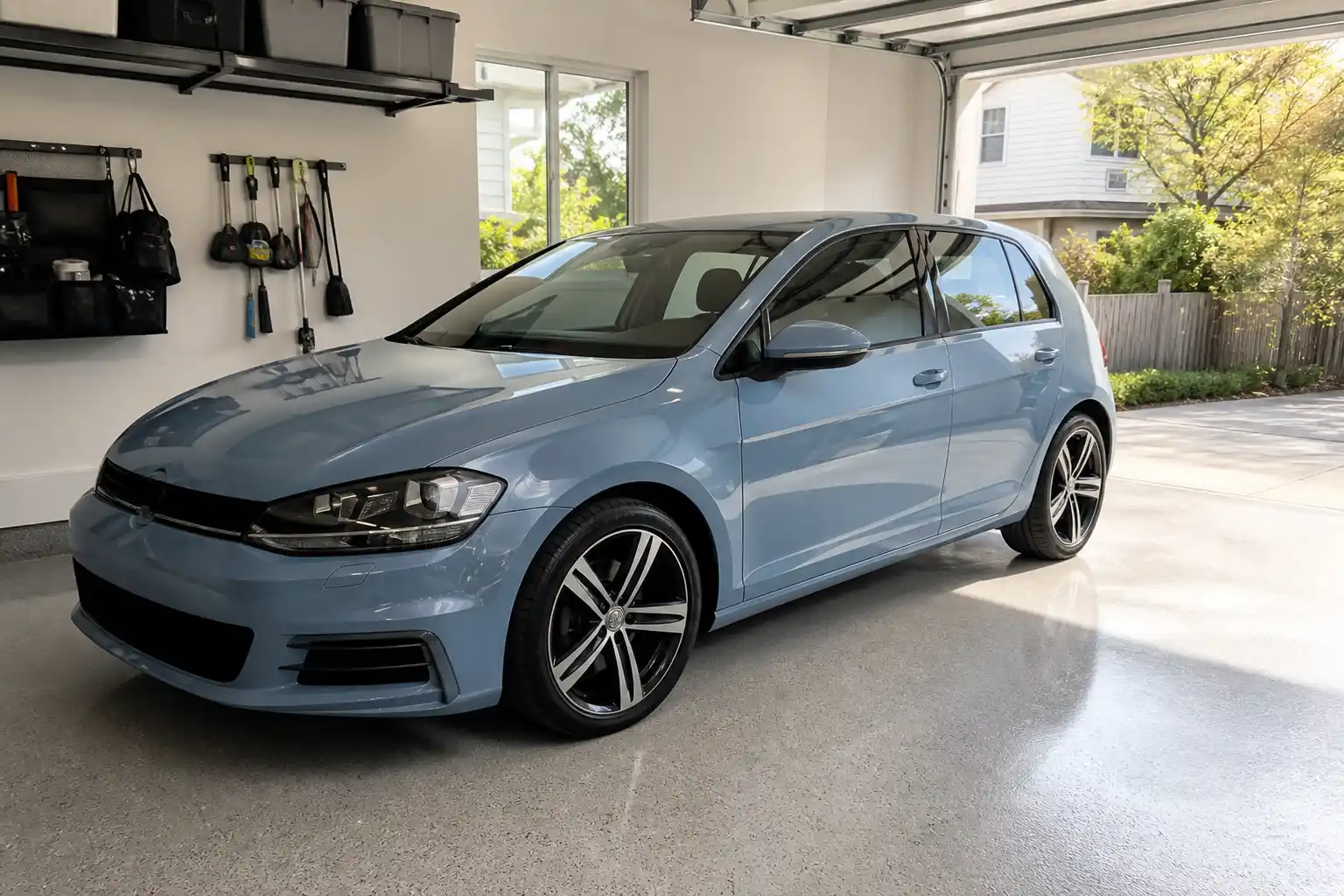 Hellblauer Kompaktwagen in einer hellen Garage mit Werkzeugwand